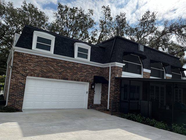 White downspouts at either end of a white garage door on a brick home