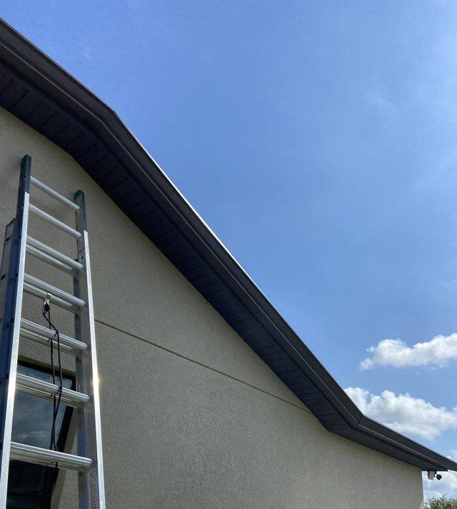 Dark bronze seamless gutter with matching soffit along a stucco gable