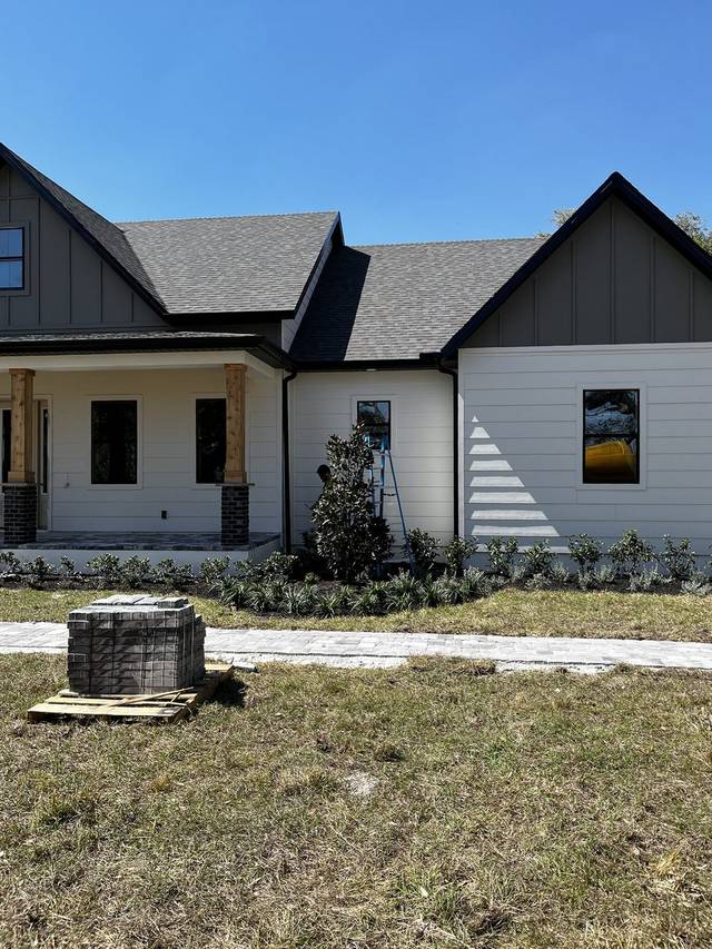Black gutters and downspouts on a new modern farmhouse, with the crew on site