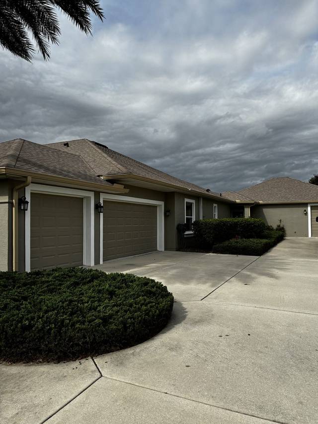 Tan gutters and downspouts across the garage front of an olive stucco home
