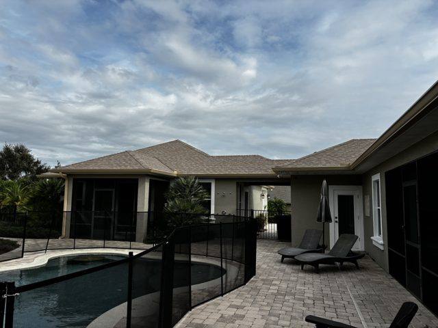 Tan gutters around a pool patio, beside a screened porch area