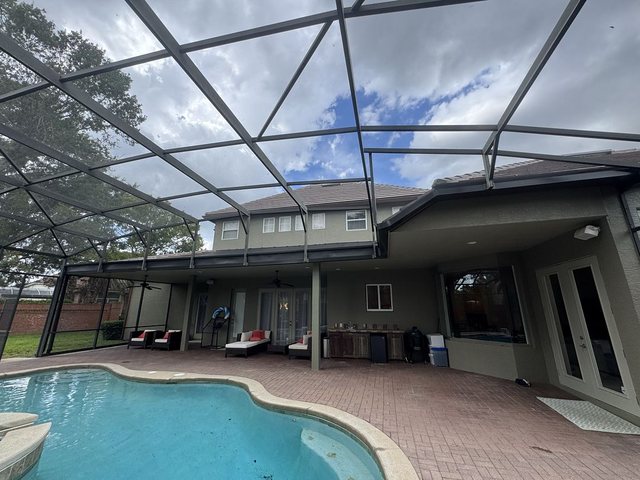 Super gutter along the roofline of a home with a screened pool enclosure