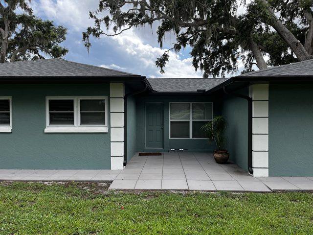 Black gutters and downspouts on a teal stucco ranch, with the downspouts running down white pilasters at the entry