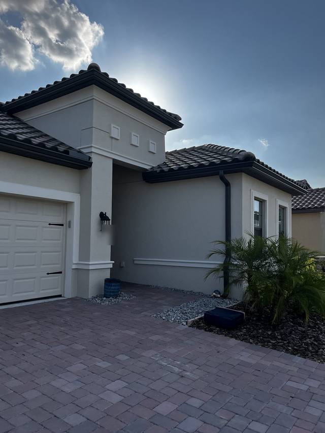 Dark gutters and a downspout at the entry of a tile-roof home
