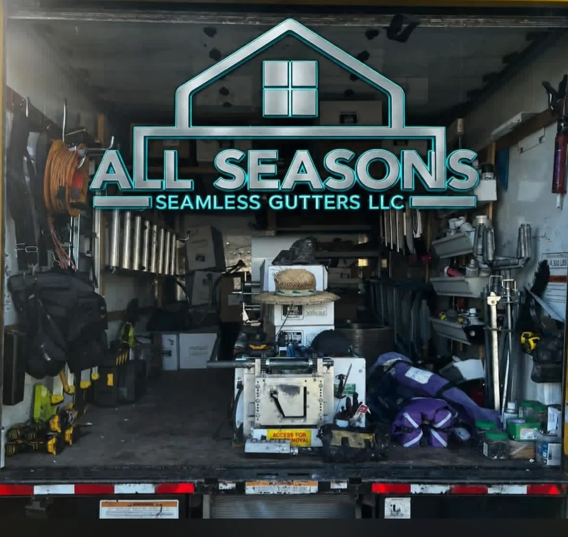 The open All Seasons Seamless Gutters work truck, loaded with tools and materials, with the company logo