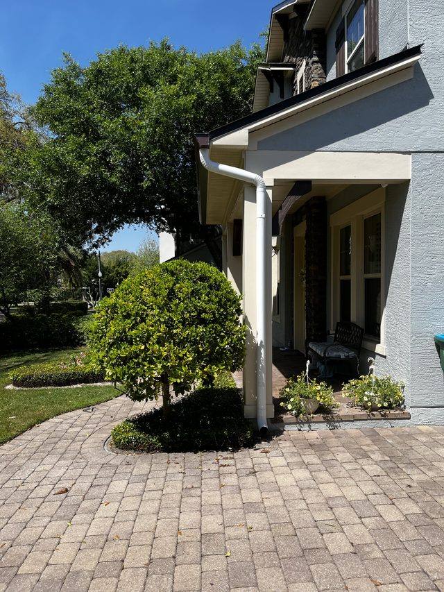 White downspout with a smooth elbow running down a front porch column